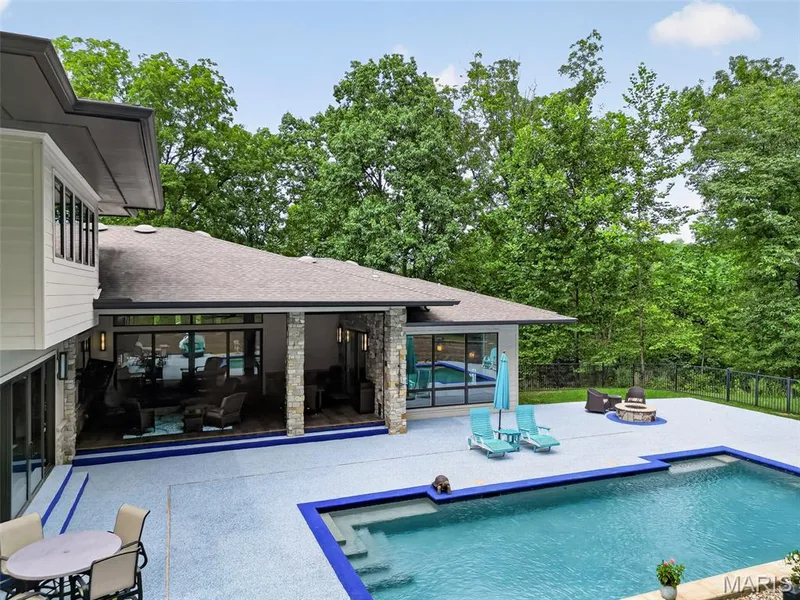 Expansive outdoor living area featuring a swimming pool, stone fire pit, and a covered patio with stone columns — 19256 Saint Albans Forest Lane, Wildwood, MO 63038