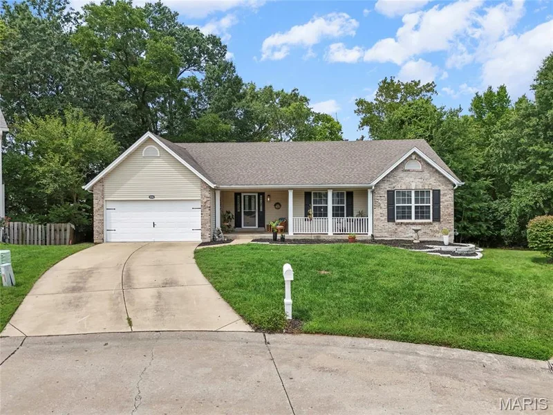 Single-story residence featuring a brick and siding exterior, an attached two-car garage, and a covered front porch with white columns — 1094 Treeshade Drive, St Peters, MO 63376