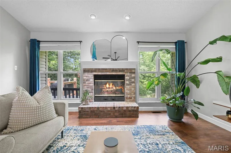 Brick fireplace with hearth, wood-finish flooring, recessed lighting, and large windows — 1094 Treeshade Drive, St Peters, MO 63376