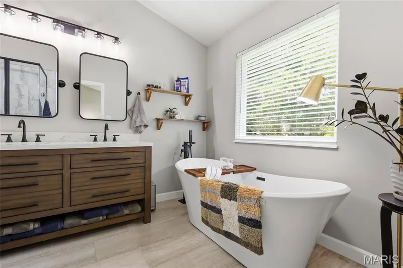 Dual vanity with wood-finish cabinetry, white countertop, and matte black fixtures — 1094 Treeshade Drive, St Peters, MO 63376