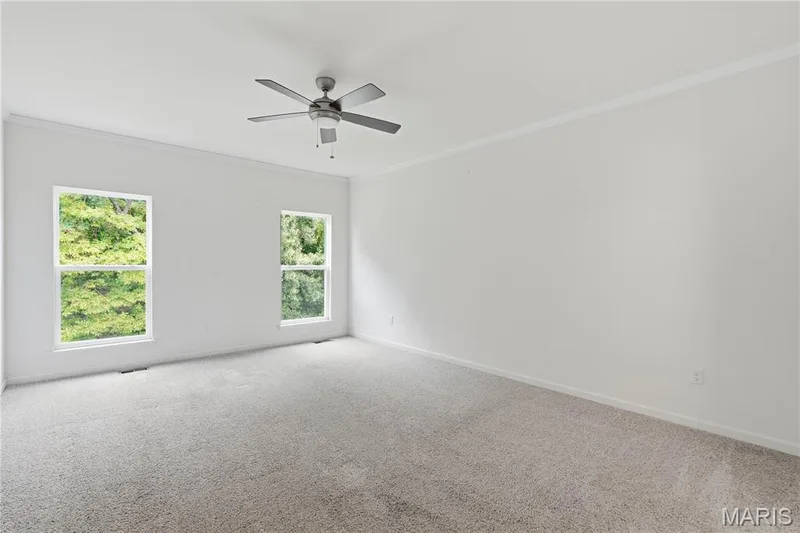 Spacious main-floor primary suite offers appealing retreat with crown molding, ceiling fan with light, and beautiful views of the woods behind the house — 1278 Harvester Drive, Chesterfield, MO 63005