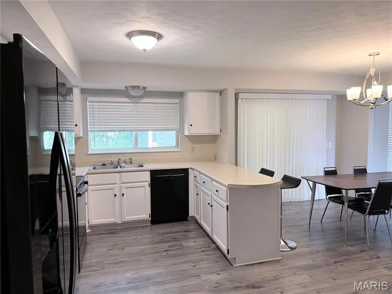 Kitchen featuring white cabinetry, light countertops, an integrated dishwasher, and wood-finish flooring — 21 White Chapel, O'Fallon, MO 63368