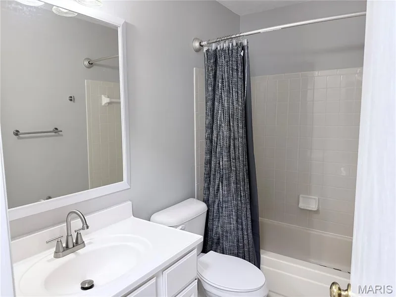 White vanity with integrated sink, brushed nickel faucet, framed mirror, and tiled shower surround with bathtub — 21 White Chapel, O'Fallon, MO 63368