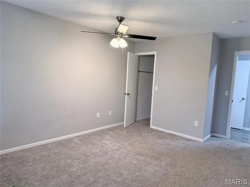 Plush carpet flooring, light-toned wall paint, a ceiling fan with integrated lighting, and white trim molding — 21 White Chapel, O'Fallon, MO 63368