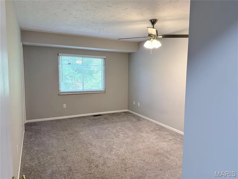 Neutral wall color, wall-to-wall carpeting, ceiling fan with integrated lighting, and window with blinds — 21 White Chapel, O'Fallon, MO 63368