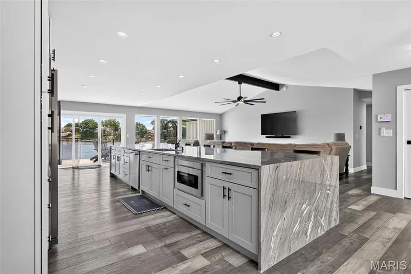 Designed for gathering—an impressive open-concept kitchen with a stunning oversized waterfall island, abundant cabinetry and beautiful lake views just beyond. — 22 Harbor Point Court, Lake St. Louis, MO 63367