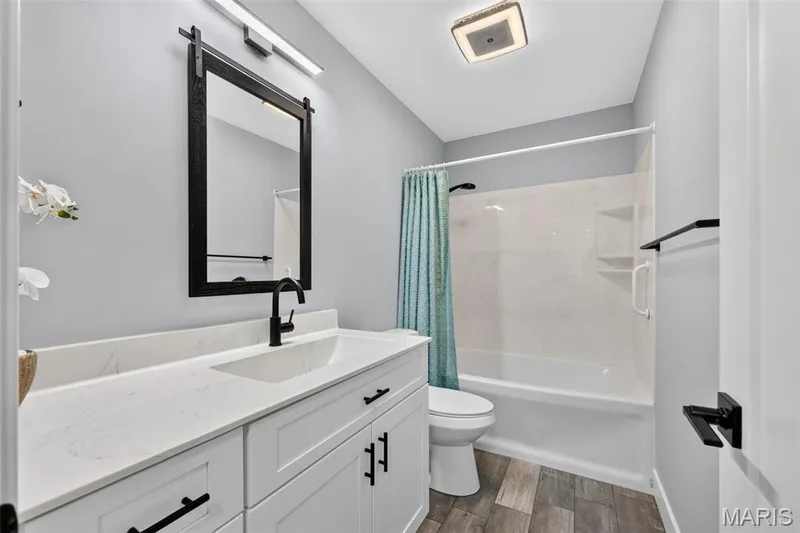 Fresh and beautifully updated hall bath featuring a spacious vanity, modern black fixtures and a tub/shower combination. — 22 Harbor Point Court, Lake St. Louis, MO 63367
