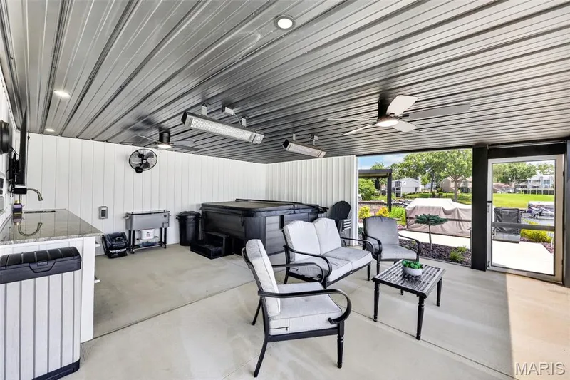 Expansive Covered Outdoor Living Area Designed for Year-Round Enjoyment! Features a Hot Tub, Outdoor Kitchen, Multiple Overhead Heaters, Ceiling and Wall Fans, TV and Plenty of Space for Dining and Entertaining all screened in and all just steps from the Pool and Lake! — 22 Harbor Point Court, Lake St. Louis, MO 63367