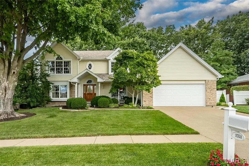 Siding exterior with brick accents, prominent two-car garage, established front landscaping, and a concrete driveway — 1551 Country Bend Drive, St Charles, MO 63303