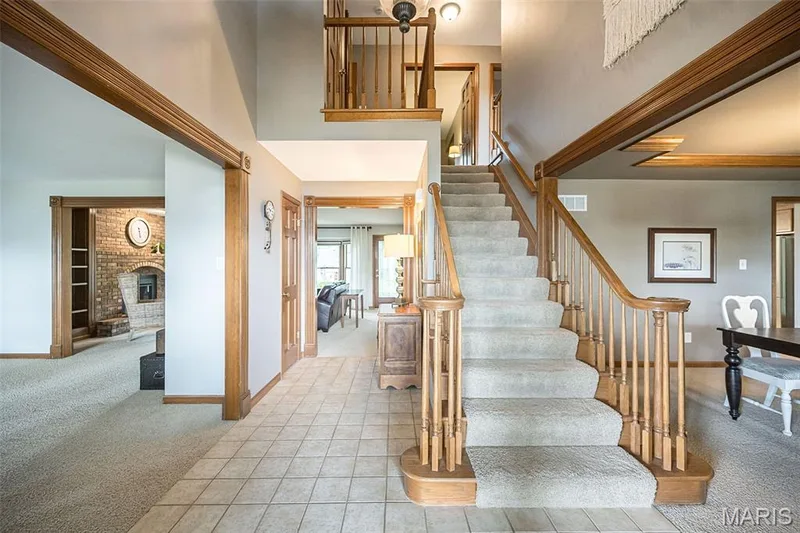 Two-story foyer with tile flooring, wood-finish staircase with carpeted treads, and wood architectural trim — 1551 Country Bend Drive, St Charles, MO 63303