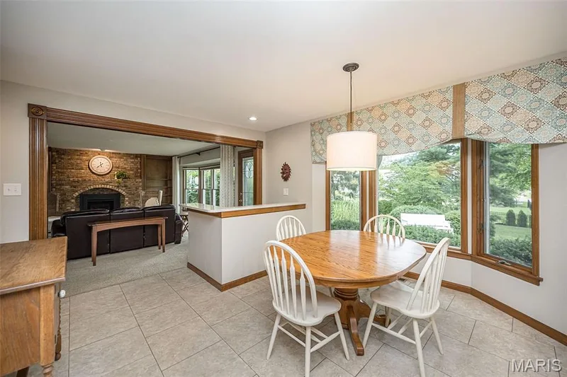 Open concept living area with tiled flooring, a decorative pendant light fixture, and a brick fireplace — 1551 Country Bend Drive, St Charles, MO 63303