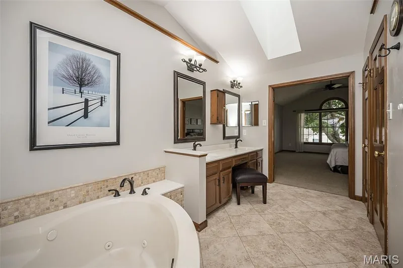 Spacious bathroom featuring a built-in jetted tub, dual vanity with undermount sinks, and tile flooring — 1551 Country Bend Drive, St Charles, MO 63303