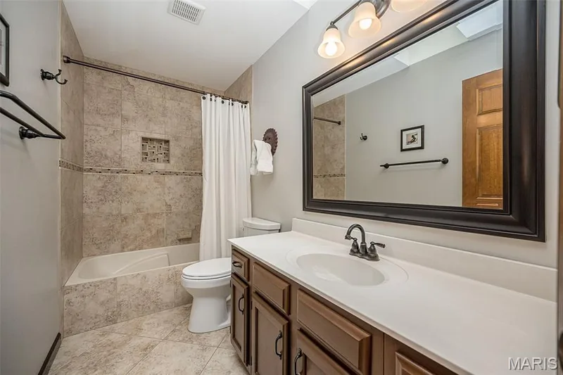 Vanity with integrated sink, dark wood-finish cabinetry, and framed mirror — 1551 Country Bend Drive, St Charles, MO 63303