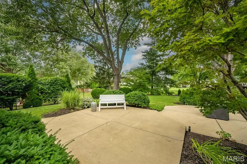 Concrete patio with surrounding landscaping, mature trees, and manicured lawn — 1551 Country Bend Drive, St Charles, MO 63303