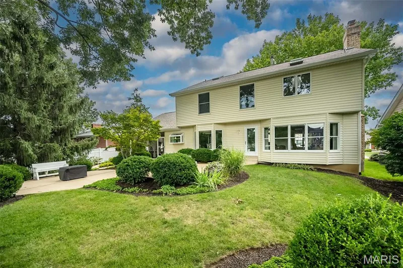 Expansive backyard featuring a manicured lawn, established landscaping, and a paver patio — 1551 Country Bend Drive, St Charles, MO 63303