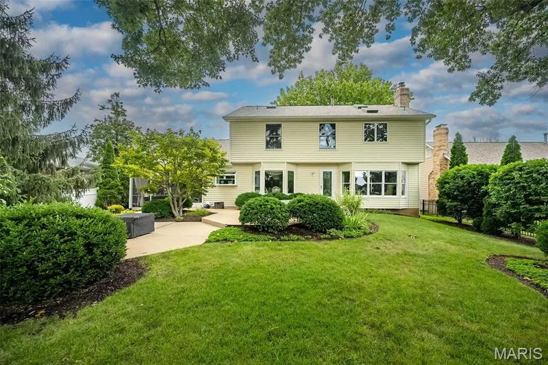 Expansive backyard featuring a manicured lawn, mature trees, and a spacious patio — 1551 Country Bend Drive, St Charles, MO 63303