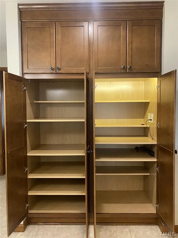 Floor-to-ceiling cabinetry with crown molding, interior shelving, and integrated lighting — 1551 Country Bend Drive, St Charles, MO 63303