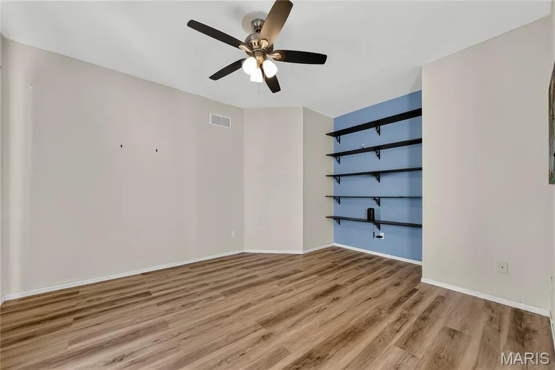 Wood-finish flooring, built-in shelving, ceiling fan with integrated lighting, two-tone wall treatment, and white baseboards — 934 Annabrook Park Drive, O'Fallon, MO 63366