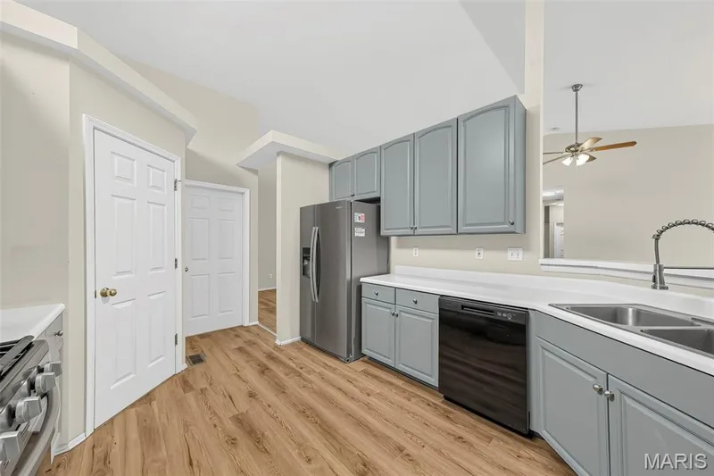 Galley kitchen with wood-finish flooring, light gray cabinetry, stainless steel appliances, and white countertops — 934 Annabrook Park Drive, O'Fallon, MO 63366