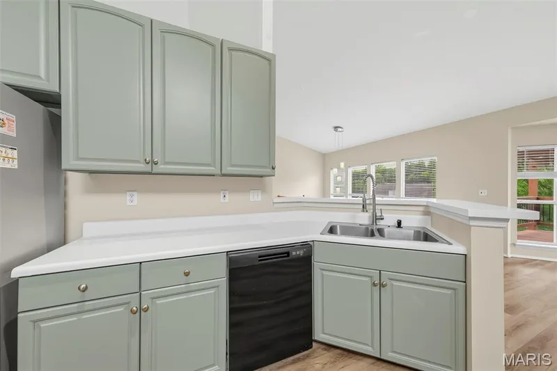 Kitchen featuring light green cabinetry, white countertops, stainless steel double-basin sink with a gooseneck faucet, and a black dishwasher — 934 Annabrook Park Drive, O'Fallon, MO 63366