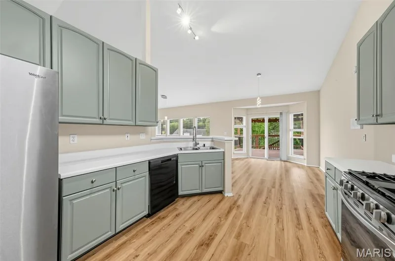 Kitchen featuring wood-finish flooring, light gray cabinetry, stainless steel appliances, and a solid surface countertop — 934 Annabrook Park Drive, O'Fallon, MO 63366