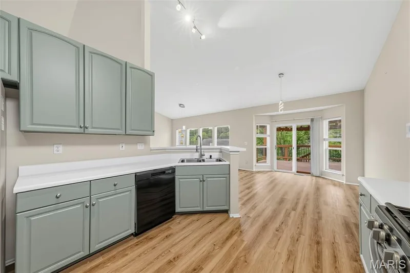 Kitchen featuring pale green cabinetry, white countertops, a stainless steel sink, and wood-finish flooring — 934 Annabrook Park Drive, O'Fallon, MO 63366