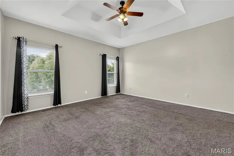 Tray ceiling with a ceiling fan, two windows, and gray wall paint — 934 Annabrook Park Drive, O'Fallon, MO 63366