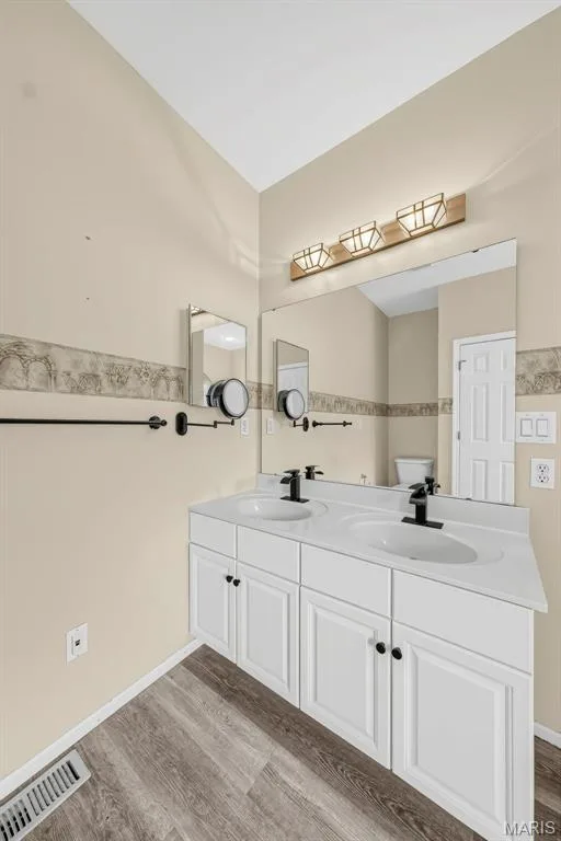 Dual vanity with white cabinetry, matte black fixtures, integrated sinks, and wood-finish flooring — 934 Annabrook Park Drive, O'Fallon, MO 63366