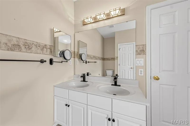 Dual vanity with integrated sinks, white cabinetry, matte black fixtures, and a large wall-mounted mirror — 934 Annabrook Park Drive, O'Fallon, MO 63366