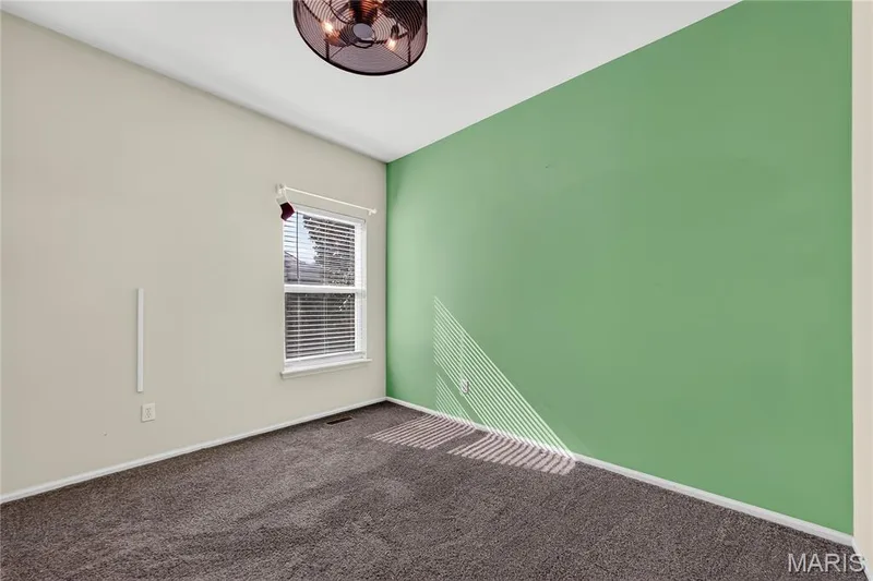 Carpeted room with a window featuring blinds, a textured ceiling, and a ceiling-mounted light fixture — 934 Annabrook Park Drive, O'Fallon, MO 63366