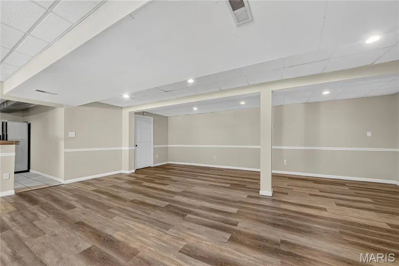 Expansive room featuring wood-finish flooring, recessed lighting, drop ceiling, and two-tone painted walls with chair rail molding — 934 Annabrook Park Drive, O'Fallon, MO 63366