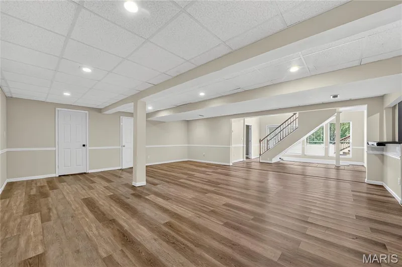 Expansive open-concept room featuring wood-finish flooring, recessed lighting, drop ceiling, and a staircase with wood handrails — 934 Annabrook Park Drive, O'Fallon, MO 63366