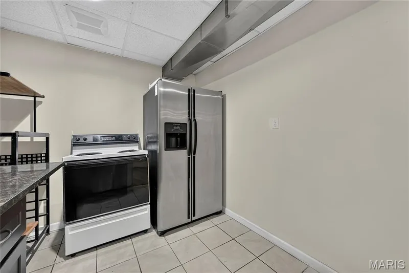 Stainless steel refrigerator, freestanding range, tiled flooring, drop ceiling, and exposed ductwork — 934 Annabrook Park Drive, O'Fallon, MO 63366