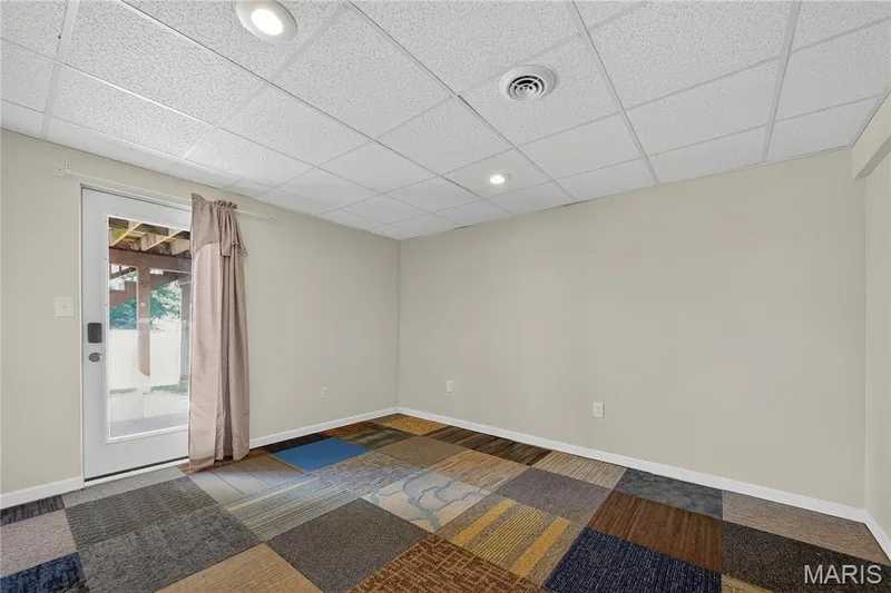 Recessed lighting, drop ceiling, full-light door, variegated carpet tile flooring, and neutral wall paint — 934 Annabrook Park Drive, O'Fallon, MO 63366