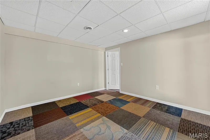 Room featuring neutral wall paint, multi-colored carpet tile flooring, and a drop ceiling with recessed lighting — 934 Annabrook Park Drive, O'Fallon, MO 63366