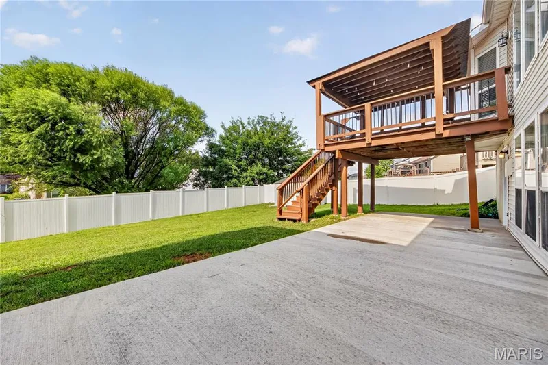Expansive concrete patio with a covered wood deck featuring a privacy fence and ample green space — 934 Annabrook Park Drive, O'Fallon, MO 63366