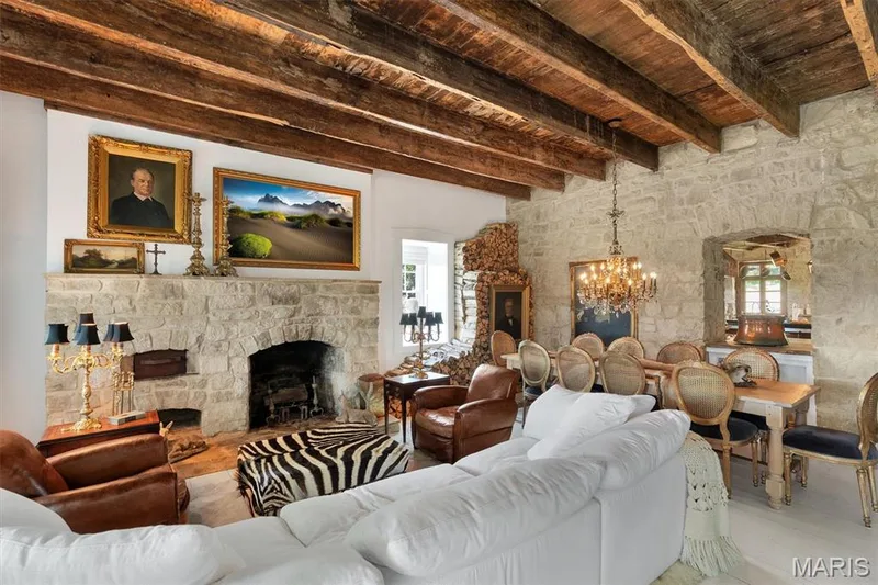 Exposed wood beam ceiling, stone-clad walls, stone fireplace with hearth, arched doorway, and a chandelier — 2275 Highway F #LOT 1, Defiance, MO 63341