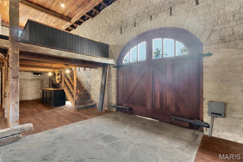 Arched wooden entry doors with transom windows, stone flooring, wood-clad ceiling, exposed wood beams, and a built-in bar area — 2275 Highway F #LOT 1, Defiance, MO 63341