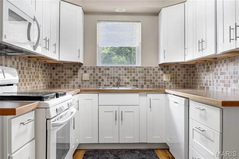 The kitchen features white cabinet and appliances. — 1401 Tamarack Drive, St Charles, MO 63301
