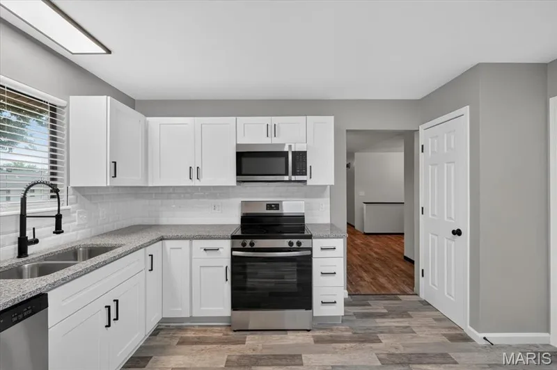 The updated kitchen  includes hard surface counters and tile backsplash. — 1688 Knightwood Lane, O'Fallon, MO 63366