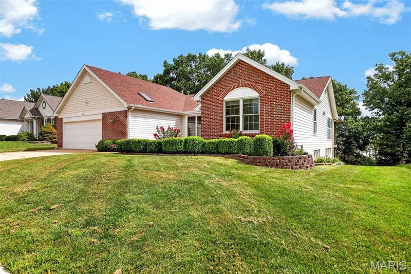 Brick and siding exterior with a two-car garage, arched window, and mature landscaping — 1420 Prospect Lakes Drive, Wentzville, MO 63385