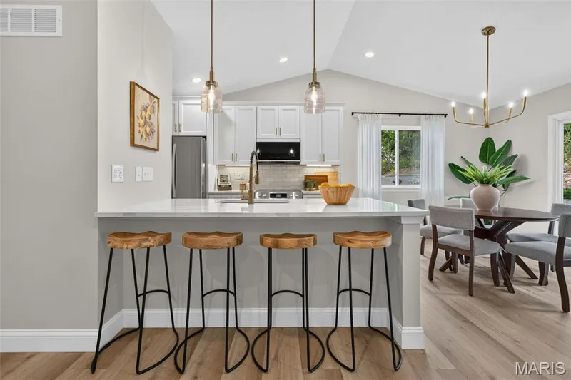 The designer kitchen features quartz countertops, 42-inch cabinetry, stainless appliances and statement lighting. — 11075 Village Drive, Foristell, MO 63348