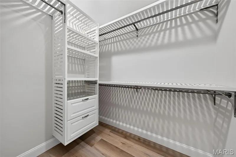 Custom closet system featuring white shelving, integrated drawers with metal pulls, and hanging rods — 11075 Village Drive, Foristell, MO 63348