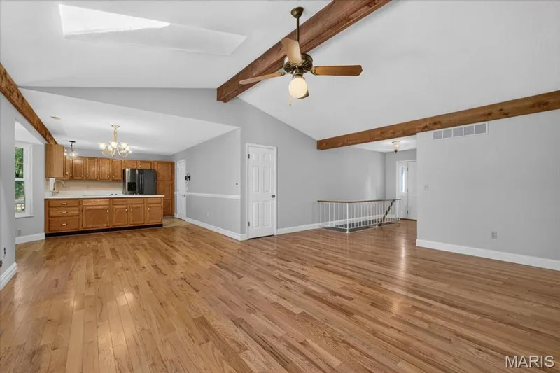Vaulted ceiling with exposed wood beams, hardwood flooring, ceiling fan, updated kitchen with wood cabinetry, and a skylight — 20 Ardennais Road, St Peters, MO 63376