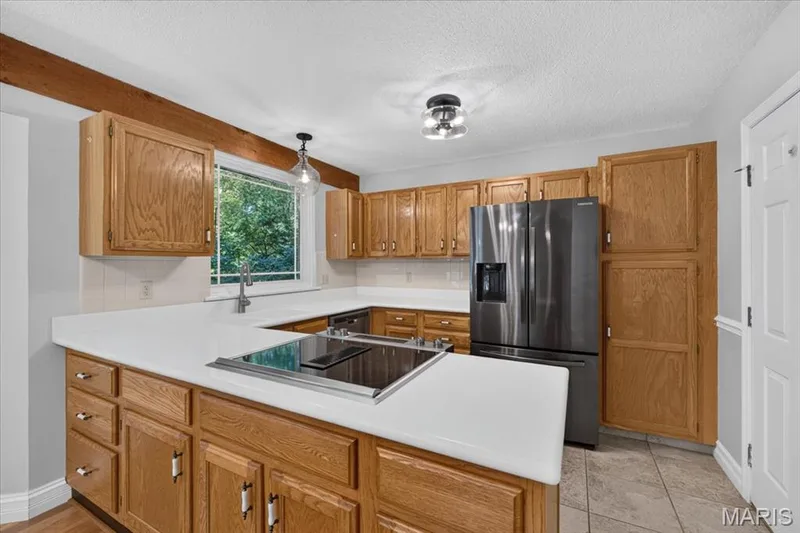 U-shaped kitchen with wood cabinetry and light-toned countertops — 20 Ardennais Road, St Peters, MO 63376