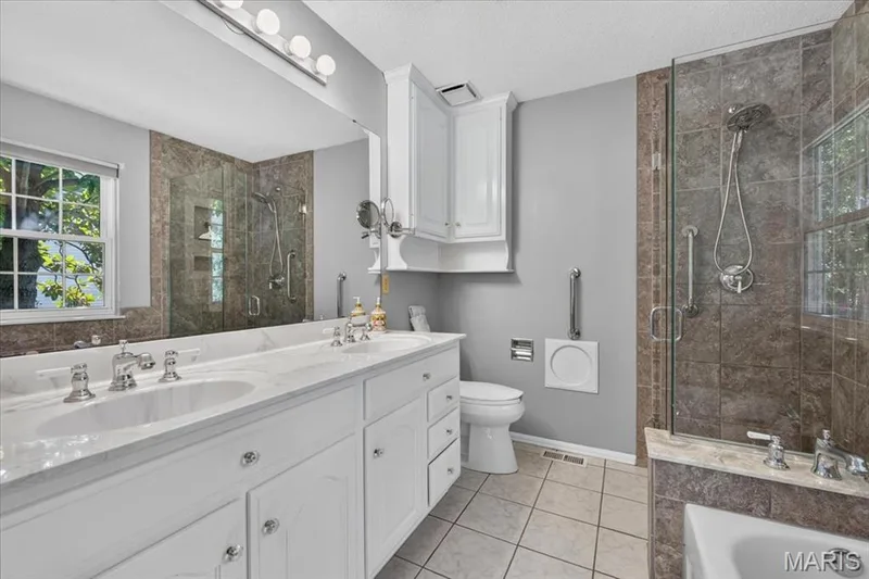 Dual vanity with undermount sinks, white cabinetry, and a large mirror — 20 Ardennais Road, St Peters, MO 63376