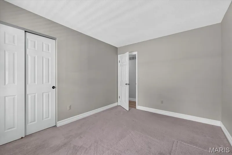 Bedroom 2- Soft gray wall paint, textured ceiling, light-colored carpeting, white panel doors, and white trim — 20 Ardennais Road, St Peters, MO 63376