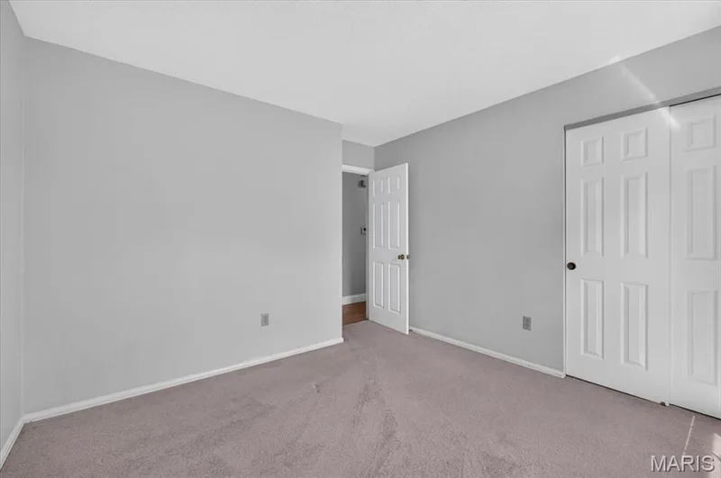 Bedroom 3- Light gray wall paint, textured ceiling, carpet flooring, white paneled doors, and interior doorway — 20 Ardennais Road, St Peters, MO 63376
