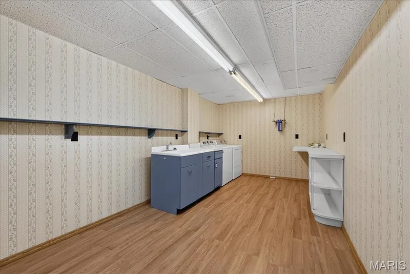 Utility room featuring wood-finish flooring, sink, built-in cabinetry, and integrated shelving — 20 Ardennais Road, St Peters, MO 63376