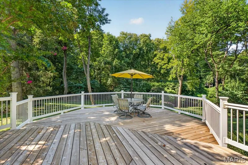 Expansive wood deck with white railings and mature perimeter trees — 20 Ardennais Road, St Peters, MO 63376